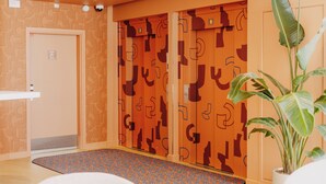 Un vestíbulo de hotel con un papel tapiz estampado, una mesa de recepción y una planta en maceta.