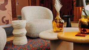 Un salón moderno con un sillón color beige, una mesita auxiliar blanca y una mesa de centro redonda.