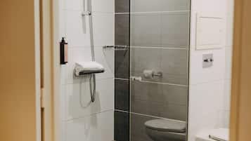 A modern bathroom with a glass shower enclosure, a toilet, and a towel rack.