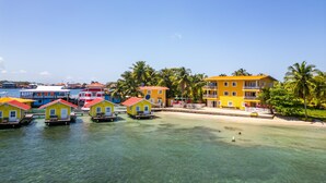A waterfront property with multiple colorful buildings, clear blue water, and palm trees. - El Faro del Colibri (Bocas del Toro)