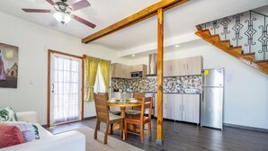 A modern kitchen with wooden cabinets, a stainless steel refrigerator, and a dining area with a table and chairs. - El Faro del Colibri (Bocas del Toro)