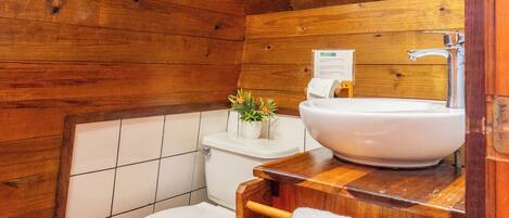 Et badeværelse i en træhytte med toilet, håndvask og håndklædestang.