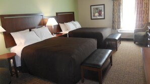 Une chambre d’hôtel avec deux lits, un bureau, une chaise et une fenêtre avec des rideaux.