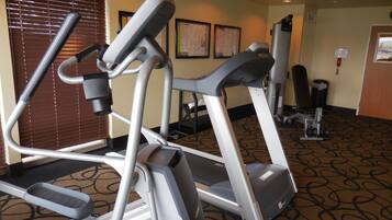 A fitness area with treadmills and elliptical machines, a patterned carpet, and a door with a window.