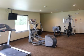 Ein Fitnessraum mit Laufband, Crosstrainer und Kraftgeräten.