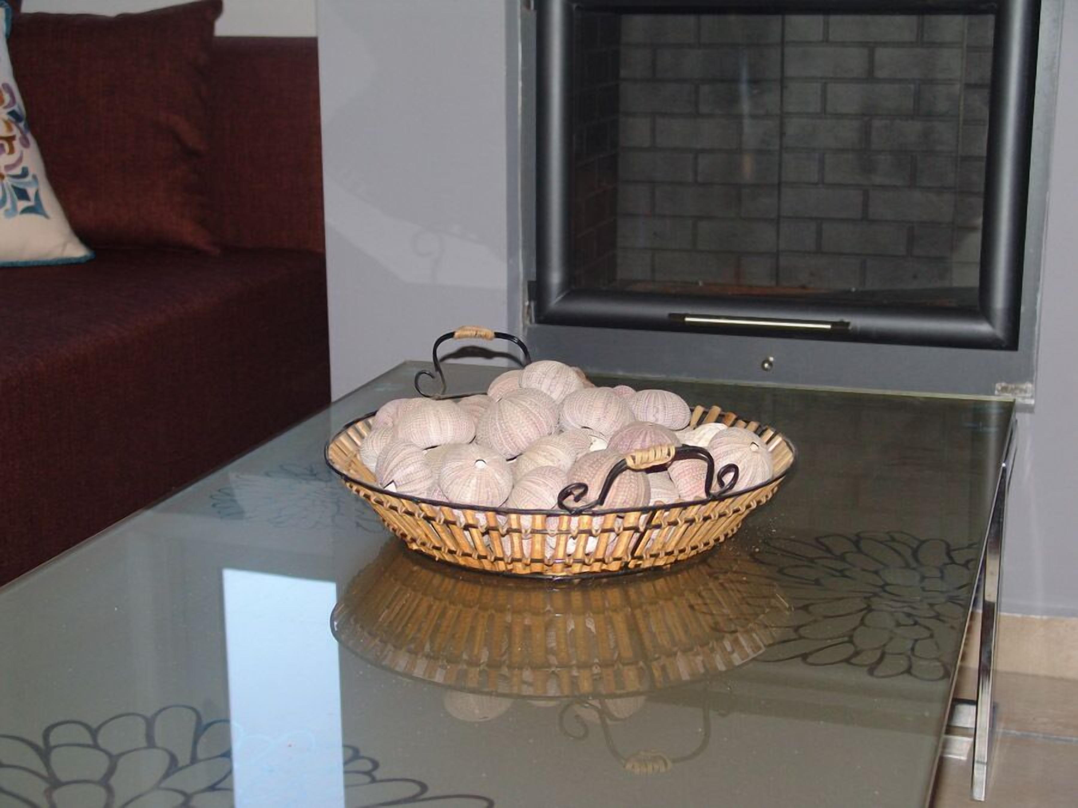 A glass-top table with a woven basket containing several round, textured objects.