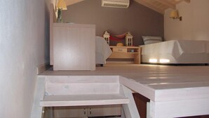 A bedroom with a sloped ceiling, a bed, a nightstand, and a dresser. - Enalia Gi (Mantoudi-Limni-Agia Anna)