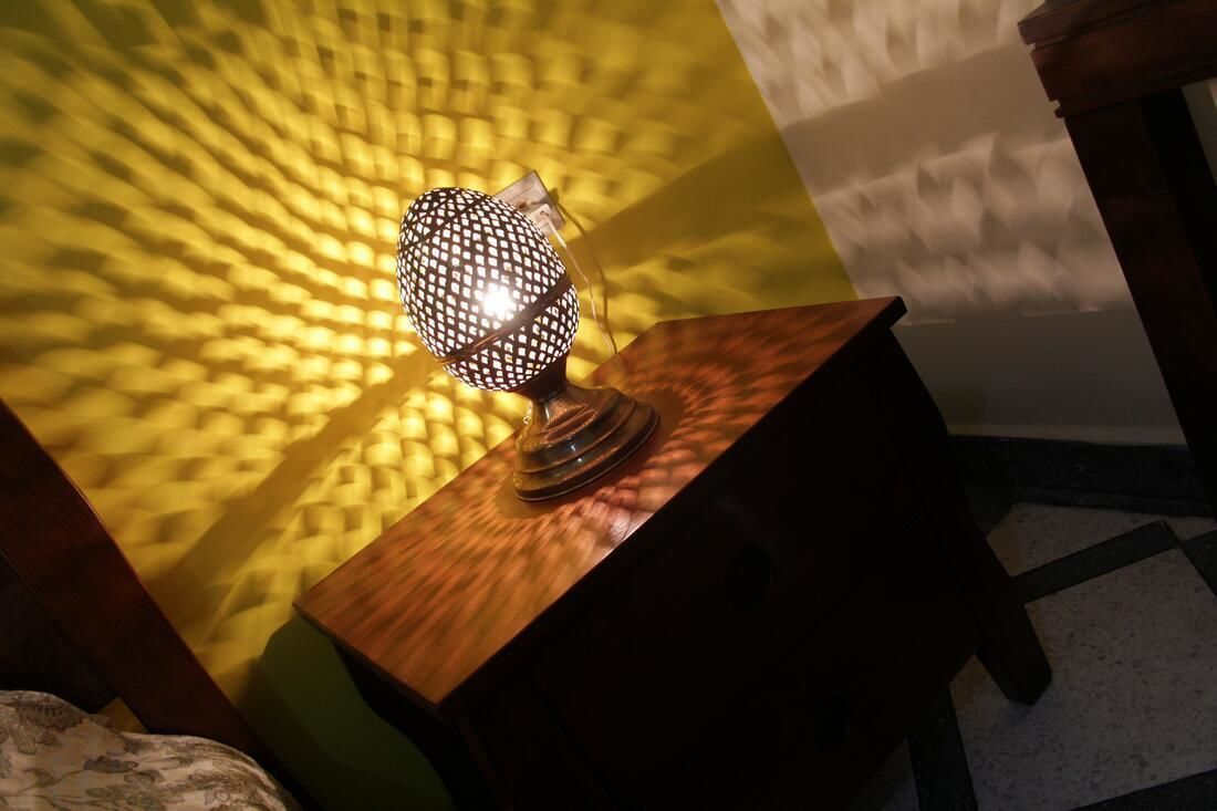 Une lampe posée sur une table en bois, avec un mur à texture en arrière-plan.