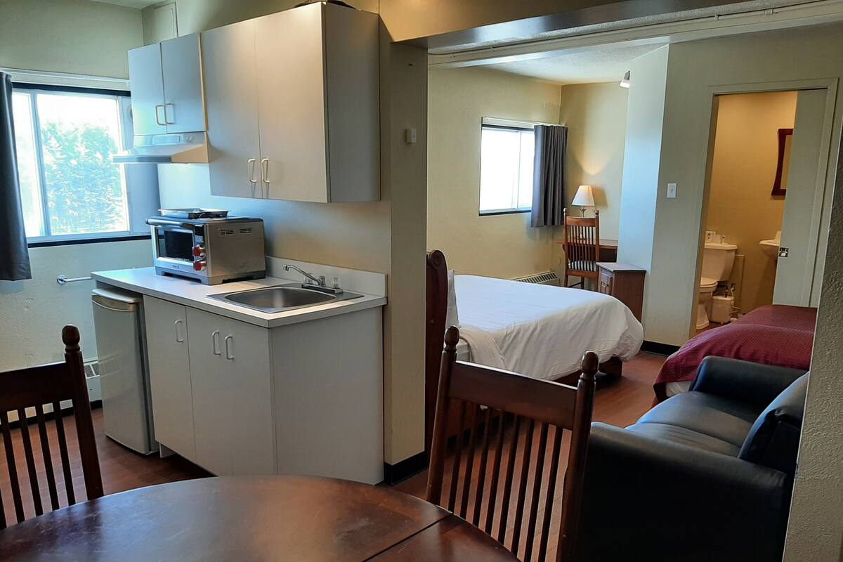 A compact room with a kitchenette, a bed, a sofa, and a dining table.