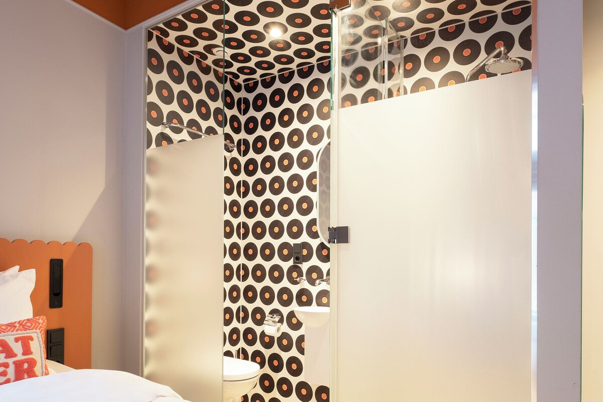 Un dormitorio con cama, armario y pared con estampado.