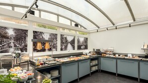 Una cocina moderna con techo de vidrio, ventanas amplias y diversos alimentos y utensilios sobre la encimera.