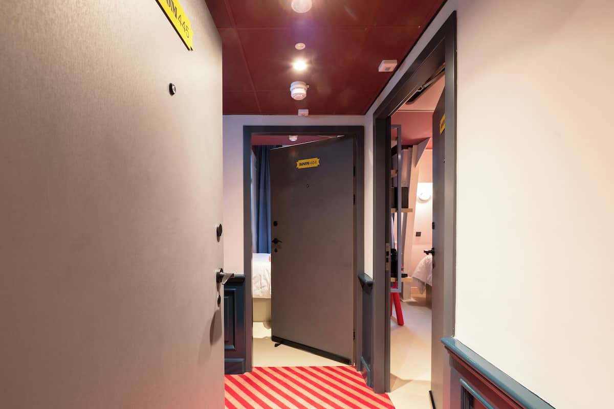 Un pasillo de hotel con alfombra a rayas, una puerta que indica 