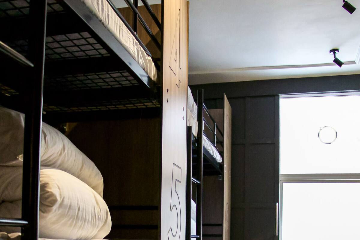 Ein Schlafraum mit Etagenbett, Fenster und Tür, die mit der Nummer 5 gekennzeichnet ist.