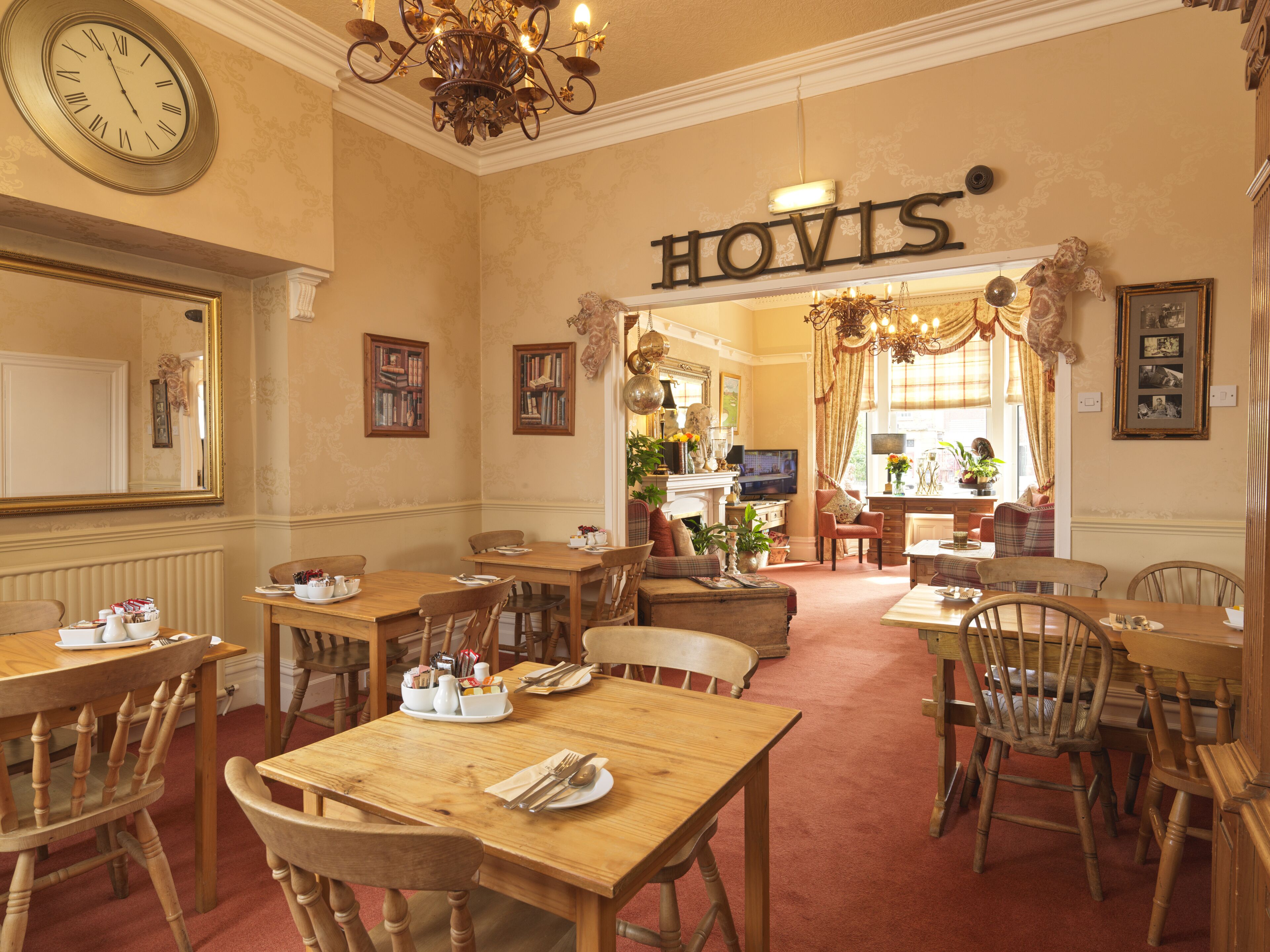 A hotel lobby with wooden furniture, a clock, and a sign reading "HOVIS".