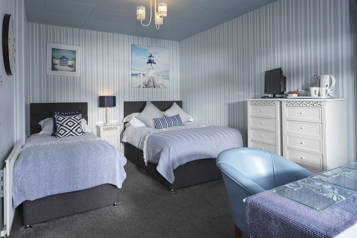A bedroom with two beds, a desk, a chair, a TV, and a cabinet.
