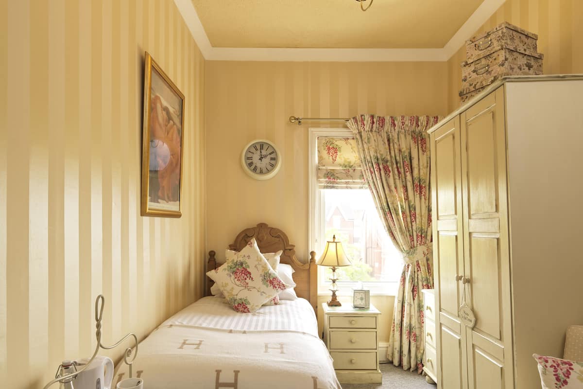 A neatly arranged bedroom with a bed, bedside table, lamp, and wardrobe.