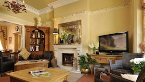 A traditional living room with a fireplace, television, and comfortable seating. - Howarth House (Lytham St. Anne's)