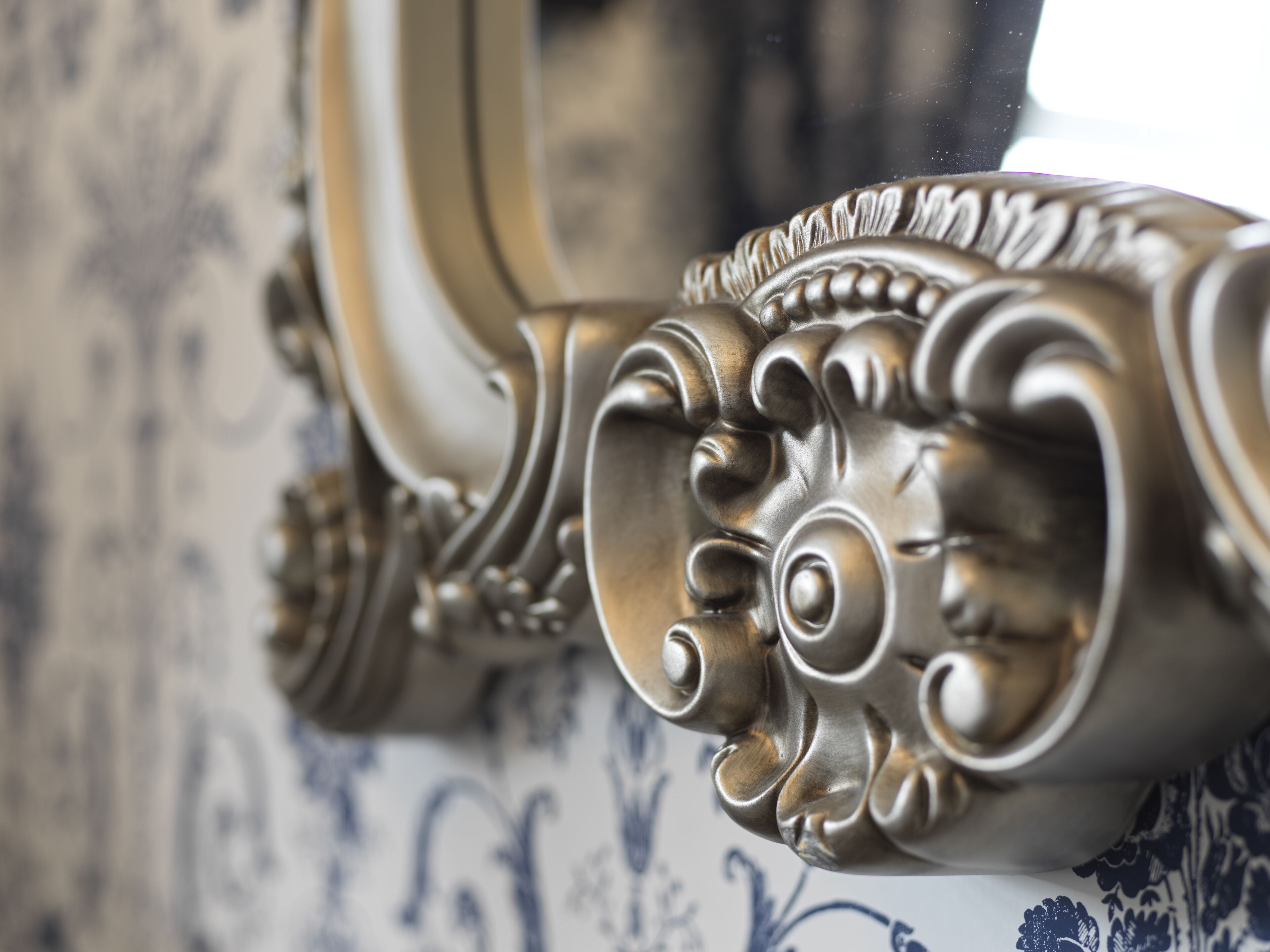 A close-up of a decorative metal rail with intricate scrollwork, likely part of a piece of furniture or a wall detail.