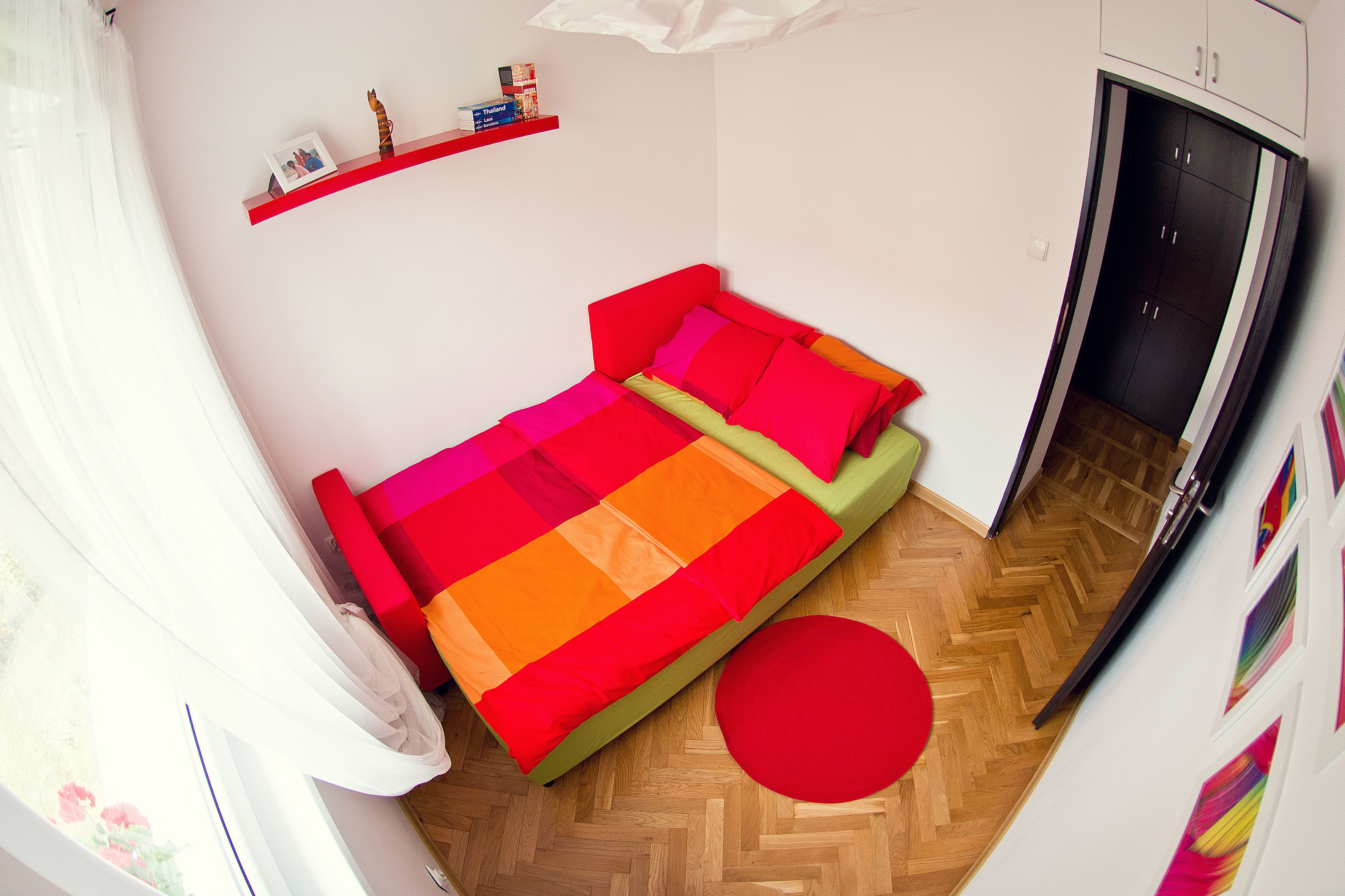 Un dormitorio compacto con una cama, un tapete rojo y un armario.
