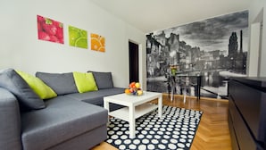 A modern living room with a grey sofa, a white coffee table with fruit, a polka dot rug, and a large black and white cityscape mural. - Fresh Apart (Bydgoszcz)
