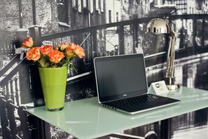 A laptop on a glass table with a green vase of flowers and a lamp in the background. - Fresh Apart (Bydgoszcz)