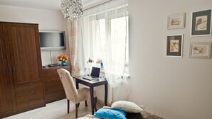 A bedroom with a bed, a desk with a laptop, a TV, and a wardrobe. - Fresh Apart (Bydgoszcz)