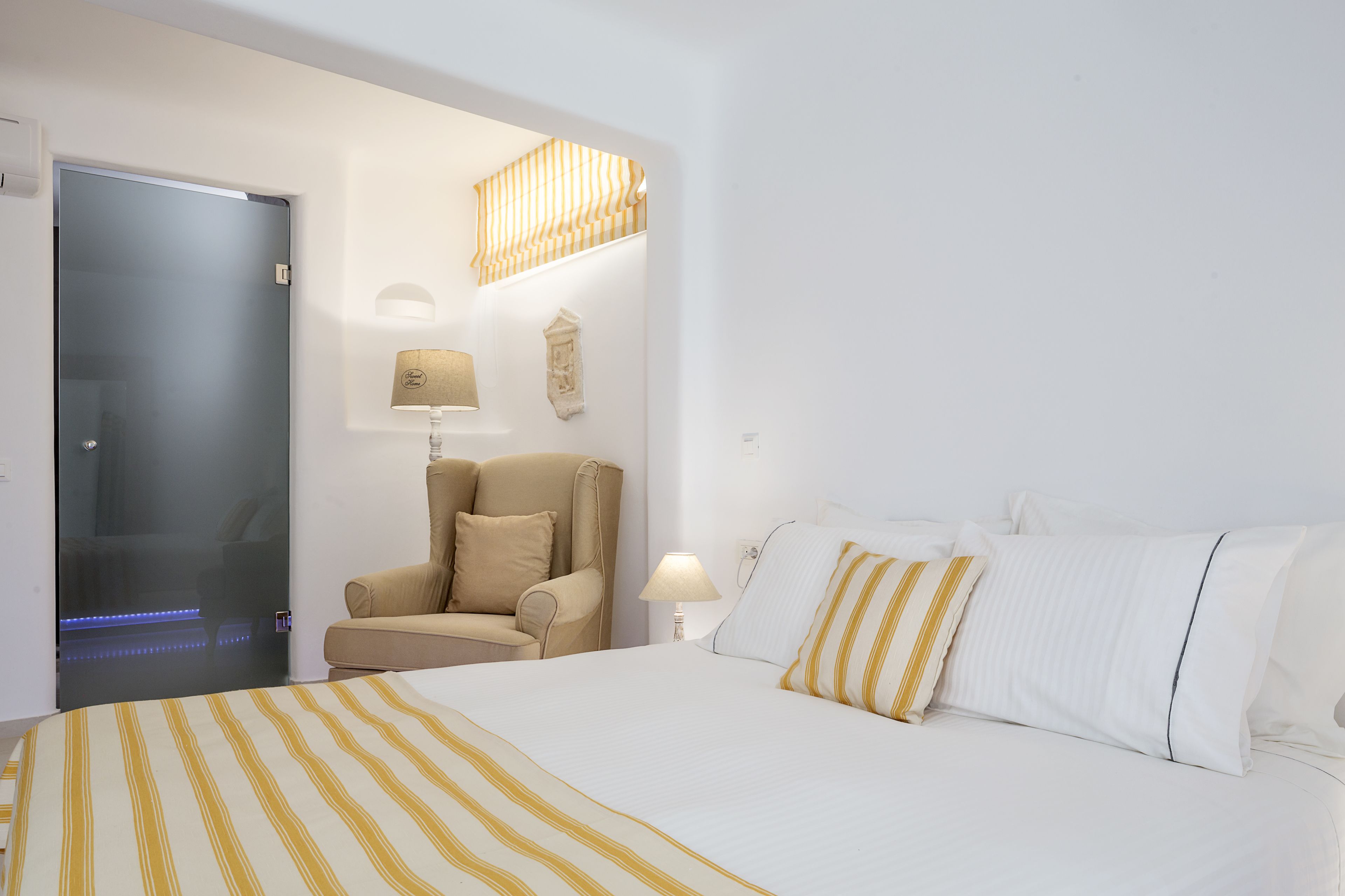 Una habitación de hotel con una cama, una silla, una lámpara y una puerta.