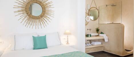 Ein Hotelzimmer mit Bett, Bad mit Dusche, Waschbecken und Spiegel.