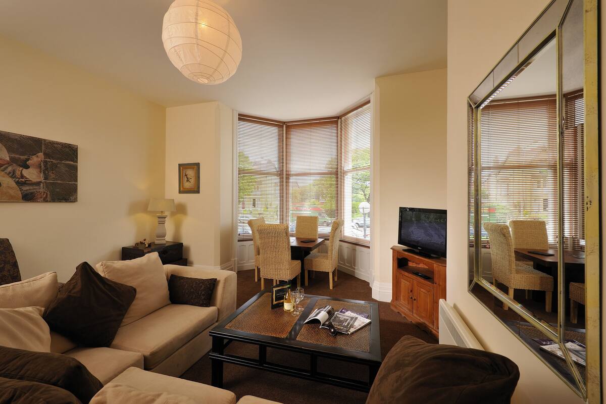 A living room with a sofa, coffee table, TV, and dining area with chairs and a table.