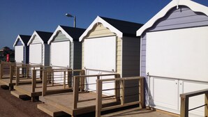 A row of beach huts with wooden decks and metal railings. - Howarth House Apartments (Lytham St. Anne's)