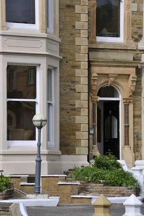 A corner building with a bay window, a door with an arch, and a number plaque.