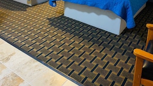 A hotel room with two beds, a patterned carpet, and a wooden chair. - Relax Inn Motel (Kountze)