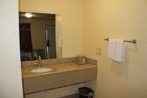 A bathroom with a sink, mirror, towel rack, and trash bin.
