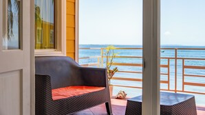 A balcony with a wicker chair and a small table, overlooking the sea. - Kevin Condos (Bocas del Toro)