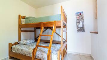 A bunk bed with a ladder, a floral bedspread, and a painting on the wall.