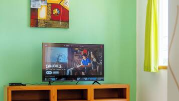 A living room with a television, wooden entertainment unit, and a ceiling fan.