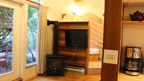 A cozy room with a wood-burning stove, a television, and a coffee maker. - Sea Star Beach Retreat (Tofino)