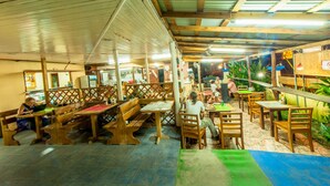 Un restaurante con muebles de madera, techo alto y suelo de baldosas.