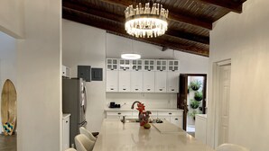 Une cuisine moderne avec des armoires blanches, un grand îlot central et un lustre.