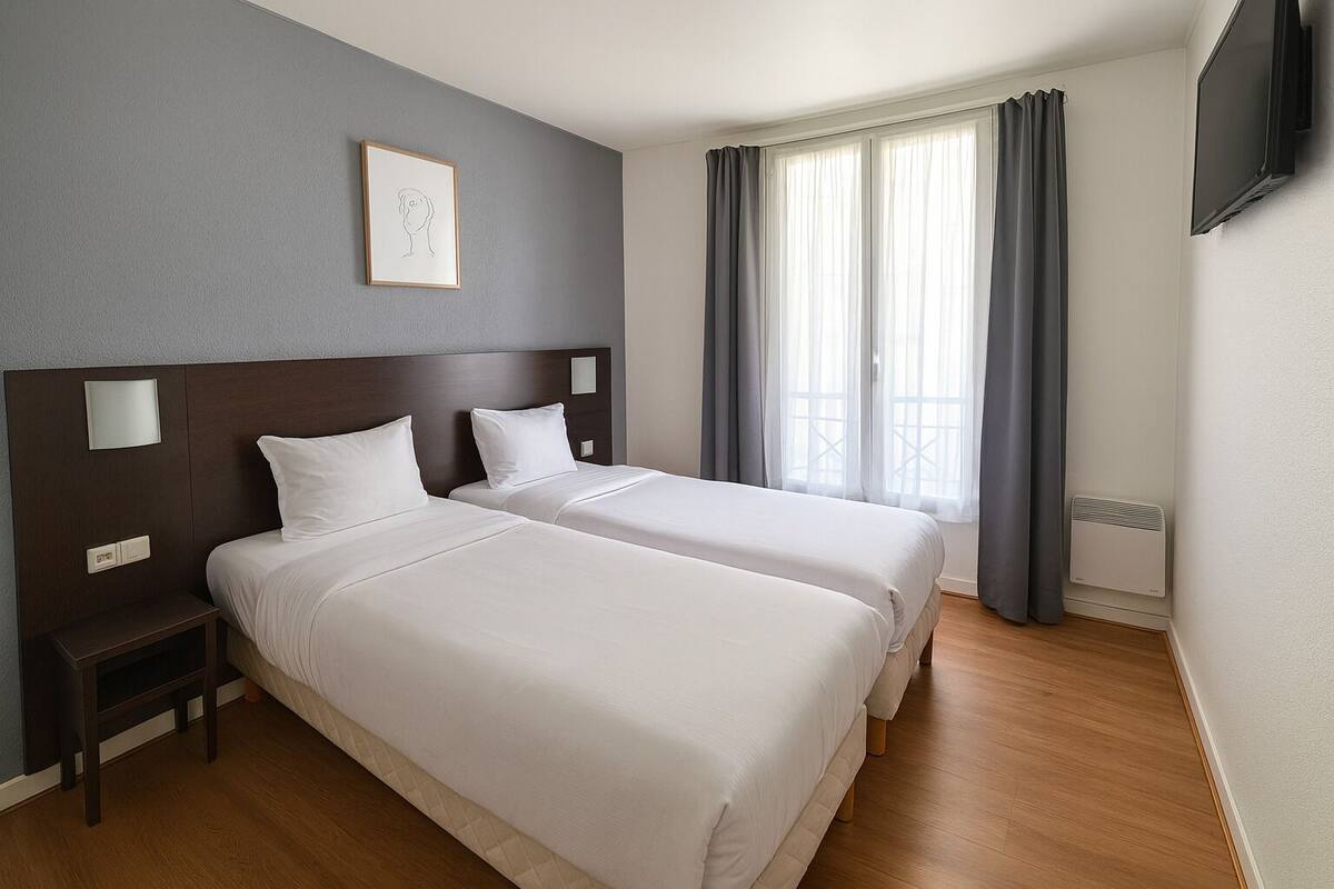 Una habitación de hotel con dos camas, una mesita de noche, un televisor y una ventana con cortinas.