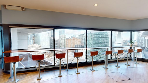 Un intérieur moderne avec de grandes fenêtres, un plancher en bois et une rangée de chaises rouges.