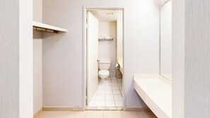 A narrow hallway leading to a bathroom with a toilet, a shower, and a sink. - Chestnut Residence - Campus Accommodation (Toronto)