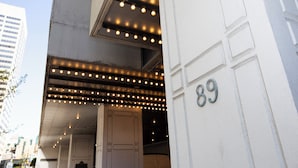 L’entrée d’un immeuble, avec un auvent et le numéro 89.
