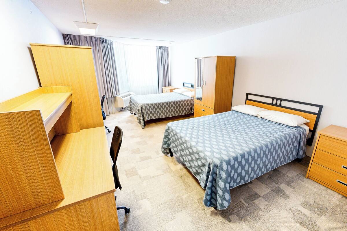 Ein Schlafzimmer mit Bett, Schreibtisch, Stuhl, Kleiderschrank und Nachttisch.