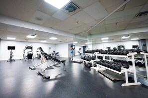 A gym with exercise equipment, dumbbells, and a mirror wall. - Chestnut Residence - Campus Accommodation (Toronto)