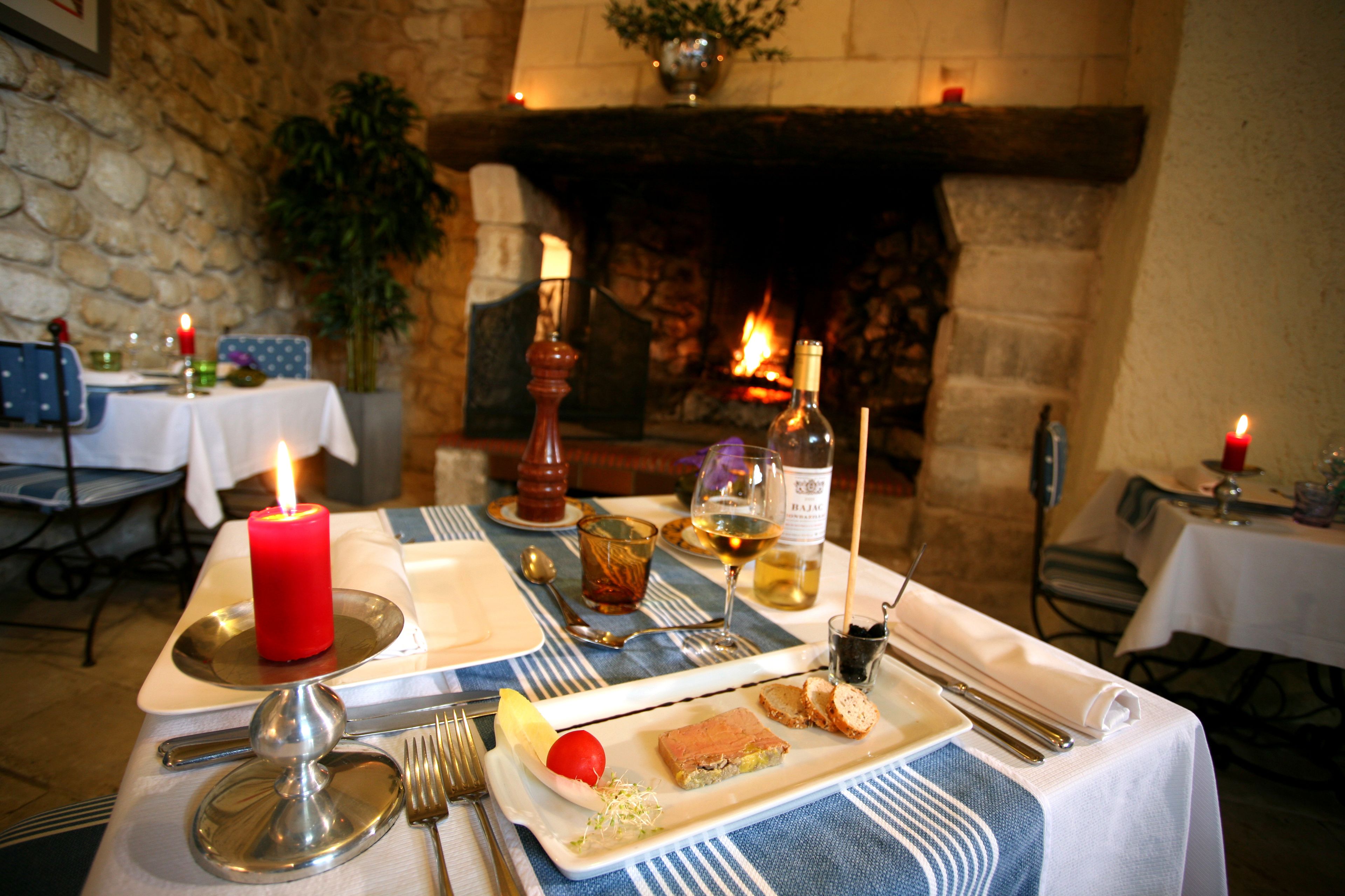 A dining table set with a red candle, wine glasses, and a plate with food.