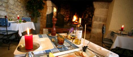 A dining table set with a red candle, wine glasses, and a plate with food.