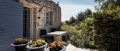 A stone building with a door, a table, and potted plants.