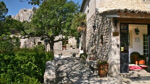 A stone building with a door marked 'R' for room, a stone staircase, and a view of a rocky hill. - Le Mas d'Aigret (Les Baux-de-Provence)