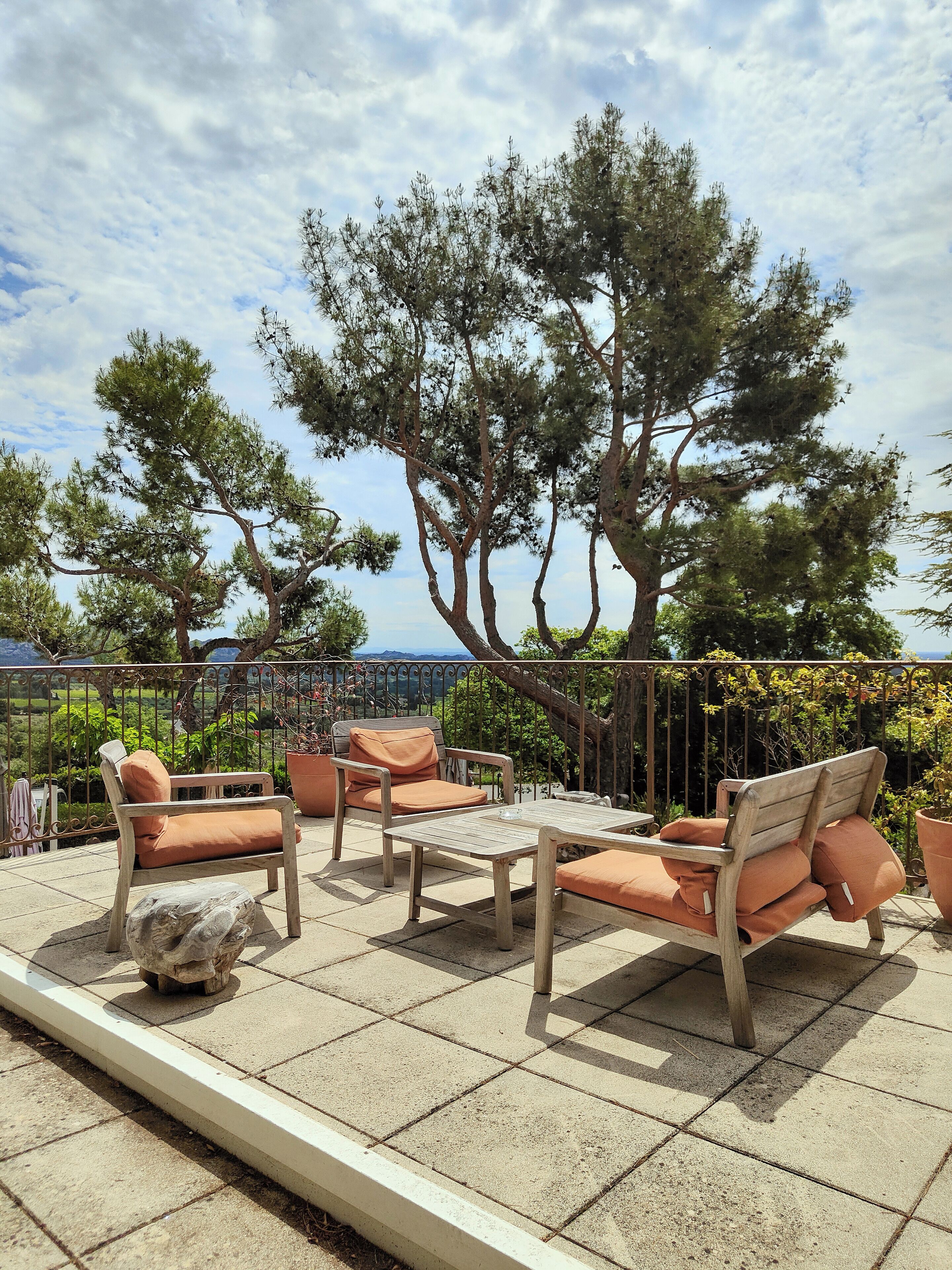 Un patio al aire libre con mobiliario de madera y vista al mar.